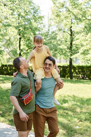 Adopted little girl walking with her family outdoors in the parkの写真素材