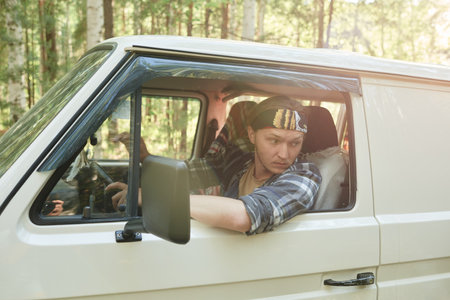 Young man driving by bus along the forest with people in the backgroundの写真素材