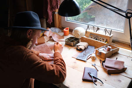 Rear view of carpenter sitting at his workplace with instruments and working in the workshop