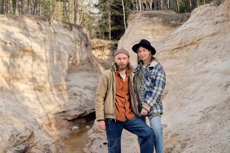 Portrait of young couple of hikers looking at camera while travelling together outdoors among the...
