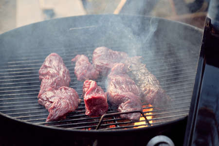 Close-up of slices of meat lying on barbecue grid and frying for dinnerの写真素材