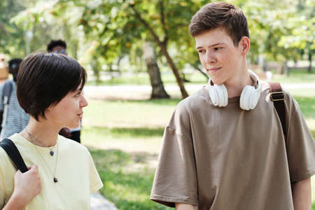 Two friends talking to each other while walking together in the parkの写真素材