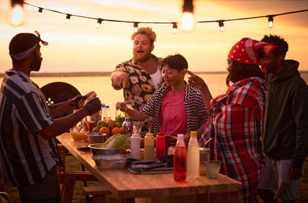 Young people eating fast food at the table during a beach party outdoorsの写真素材