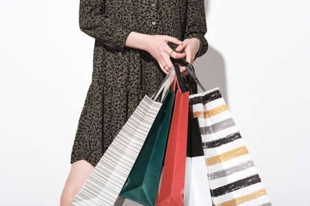Close-up of woman in elegant dress holding shopping bags isolated on white backgroundの写真素材
