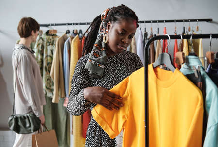 African young woman buying new clothes for herself in the shopping mallの写真素材