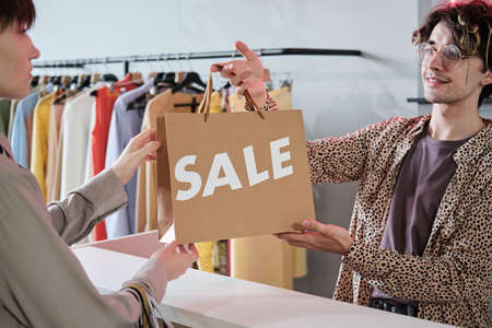 Woman taking shopping bag from the seller, she doing shopping during sale in the storeの写真素材