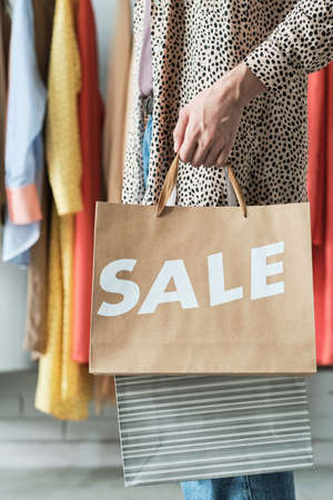 Close-up of woman in dress carrying shopping bags during sale in the shopping mall