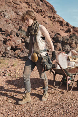 Young woman carrying heavy cart with her stuffs in the desertの写真素材