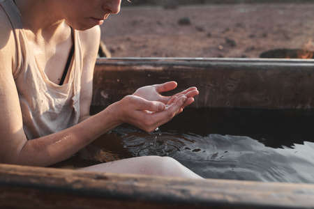 Close-up of young woman sitting in the bath outdoors and washing her faceの写真素材
