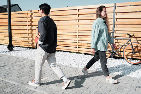 Horizontal long shot of modern unacquainted young Asian and Caucasian women spending sunny summer...