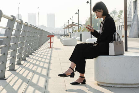 Horizontal side view shot of attractive young Asian woman wearing fashionable elegant outfit sitting...