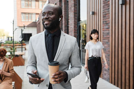 Portrait of confident African American man wearing stylish elegant gray suit standing outdoors...