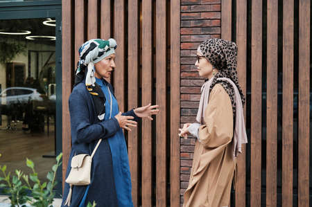 Two muslim women in traditional clothing talking to each other while meeting in the centre of the cityの写真素材