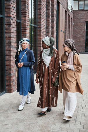 Group of muslim women talking to each other and drinking coffee during their walk in the cityの写真素材