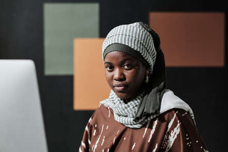 Close-up of Africa young businesswoman in hijab looking at camera while sitting at officeの写真素材