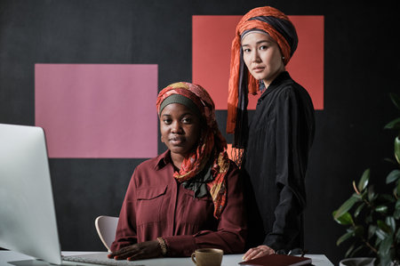 Portrait of muslim businesswomen looking at camera while working at the table on computer at officeの写真素材