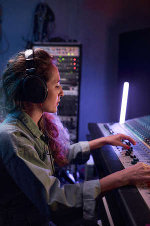 oung music producer in headphones recording a song on musical keyboard in the music studio