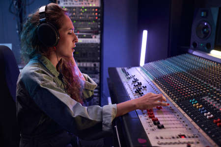 Radio DJ in headphones using music keyboard to play the music during broadcasting