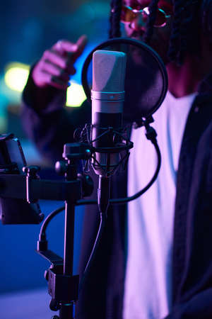 Close-up of microphone in the recording studio with singer singing in the background