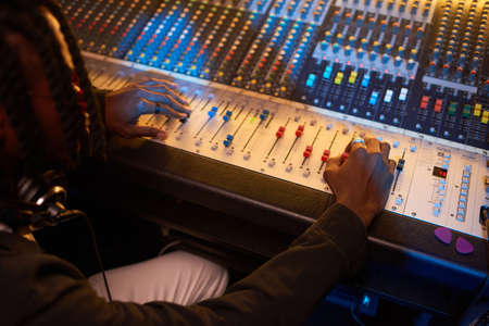 Close-up of producer creating a new song using electric music keyboard in the studio