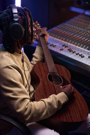 Close-up of African young man playing guitar to write a new song in the recording studioの写真素材