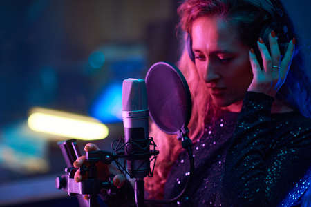 Beautiful singer in headphones writing a new song in the recording atudioの写真素材