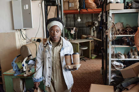 African young woman having a break at her work she carrying lunch box and coffee drinks