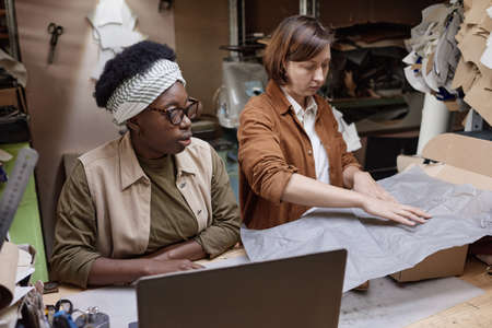 Two women sitting at the table and working in team, they packing boxes in the workshopの写真素材