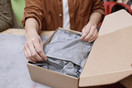 Close-up of woman packing things in box to deliver parcel to the customerの写真素材
