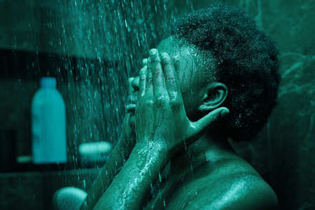 African young woman with black curly hair having a shower in the bathroomの写真素材