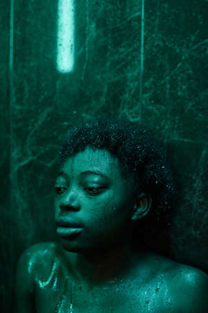 African young woman in depression leaning on the wall while washing in the showerの写真素材