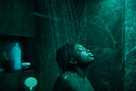 African young woman enjoying the spa procedure in the shower, she washing her hairの写真素材