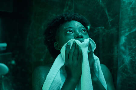 African young woman wiping her face with towel after showerの写真素材