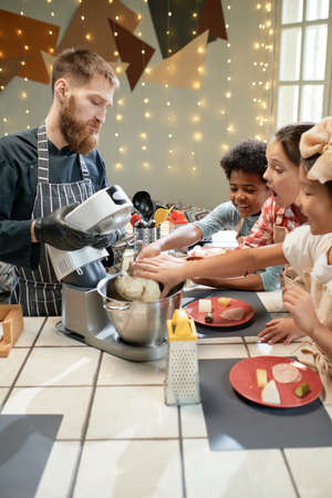 Group of children learning to cook with the help of the cook, they using mixer in their preparation in the kitchenの写真素材