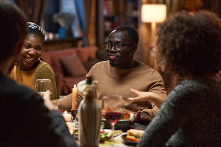 African young man sitting at dining table during a meeting with his friends at home