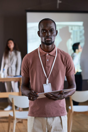 Portrait of African serious businessman with report looking at camera, he performing at the seminar