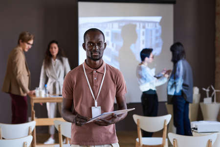 Portrait of young African businessman holding his report looking at camera, he taking part at business seminarの写真素材