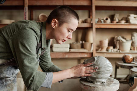 Young woman making human face from clay, she creating clay sculptures in the workshopの写真素材