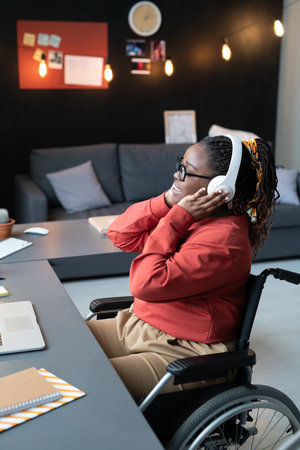 African woman sitting on wheelchair and singing a song, she enjoying the music in her headphonesの写真素材