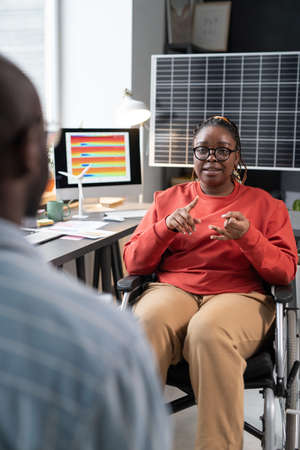 African businesswoman sitting on wheelchair and discussing work with businessman while they sitting...