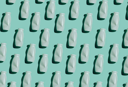 Modern seamless pattern flat lay shot of white plastic bottles on bluish green background, conscious consumption and plastic waste conceptの写真素材