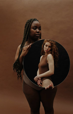 Portrait of African overweight woman standing against the brown background and holding portrait of...