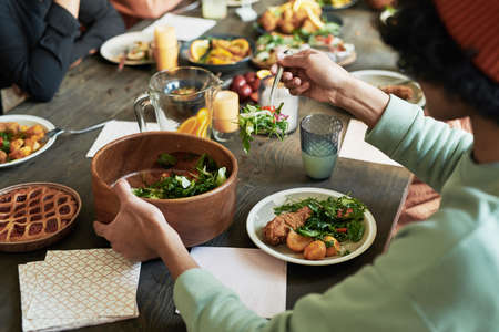 Close-up of teenage boy eating vegetable salad with chicken at dining table during holiday dinner with familyの写真素材