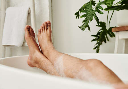 Close-up of man lying in bath with foam and relaxing during spa procedure