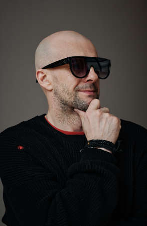 Vertical medium close-up studio portrait of confident stylish mature Caucasian man wearing sunglasses looking awayの写真素材