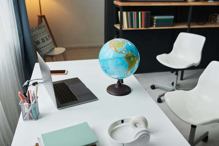 Horizontal high angle view no people shot of globe, laptop, notebooks, headphones and stationery on table in modern students room at homeの写真素材