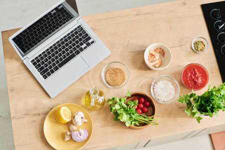 Top-down no people flat lay shot of wireless laptop and fresh food ingredients prepared for cooking on kitchen counterの写真素材
