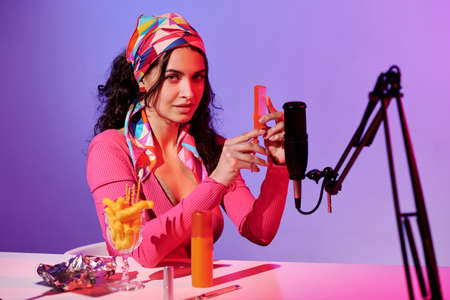 Stylish young Caucasian woman creating ASMR content recording scratching sound of hair comb looking...