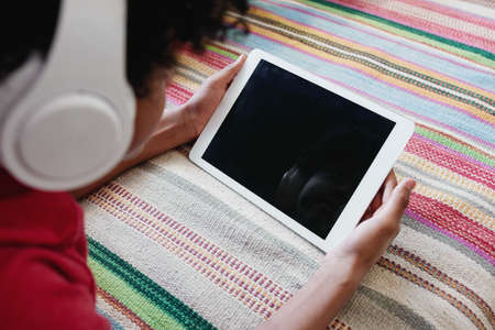 Close-up of boy in wireless headphones looking at screen of digital tablet and watching movie onlineの写真素材