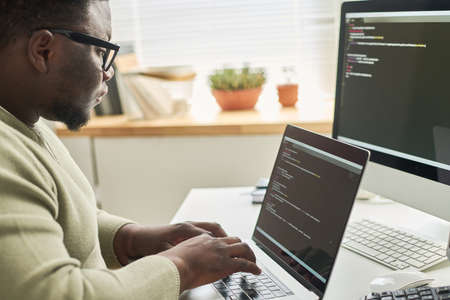 Programmer typing data code while working on project in software development companyの写真素材